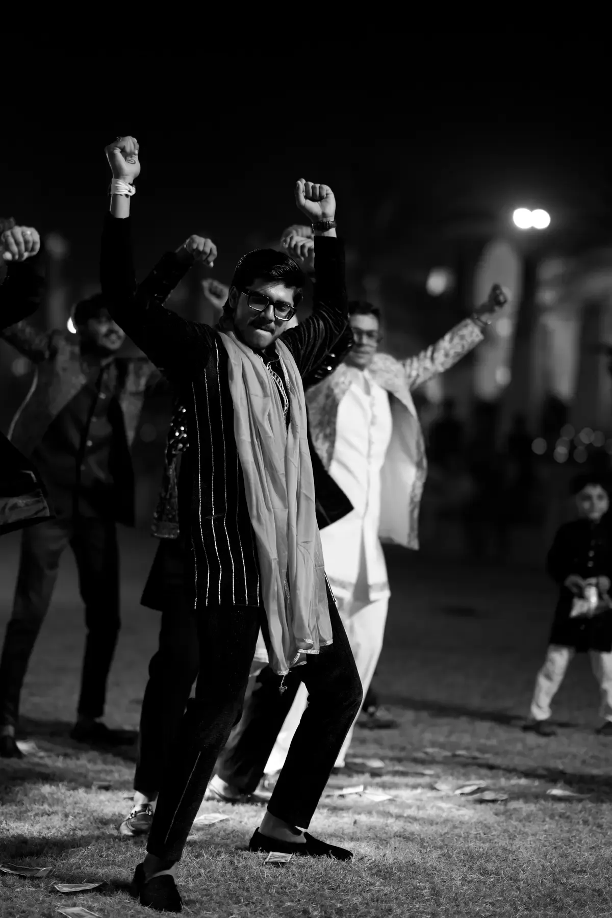 Groom dancing with friends at a wedding celebration in black and white